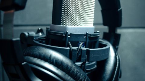 Close-up of condenser microphone with headphones in a music studio.
