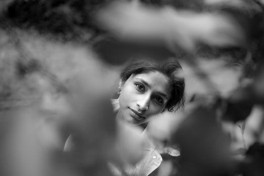 Black and white portrait of a woman through blurred leaves in Dublin, Ireland.
