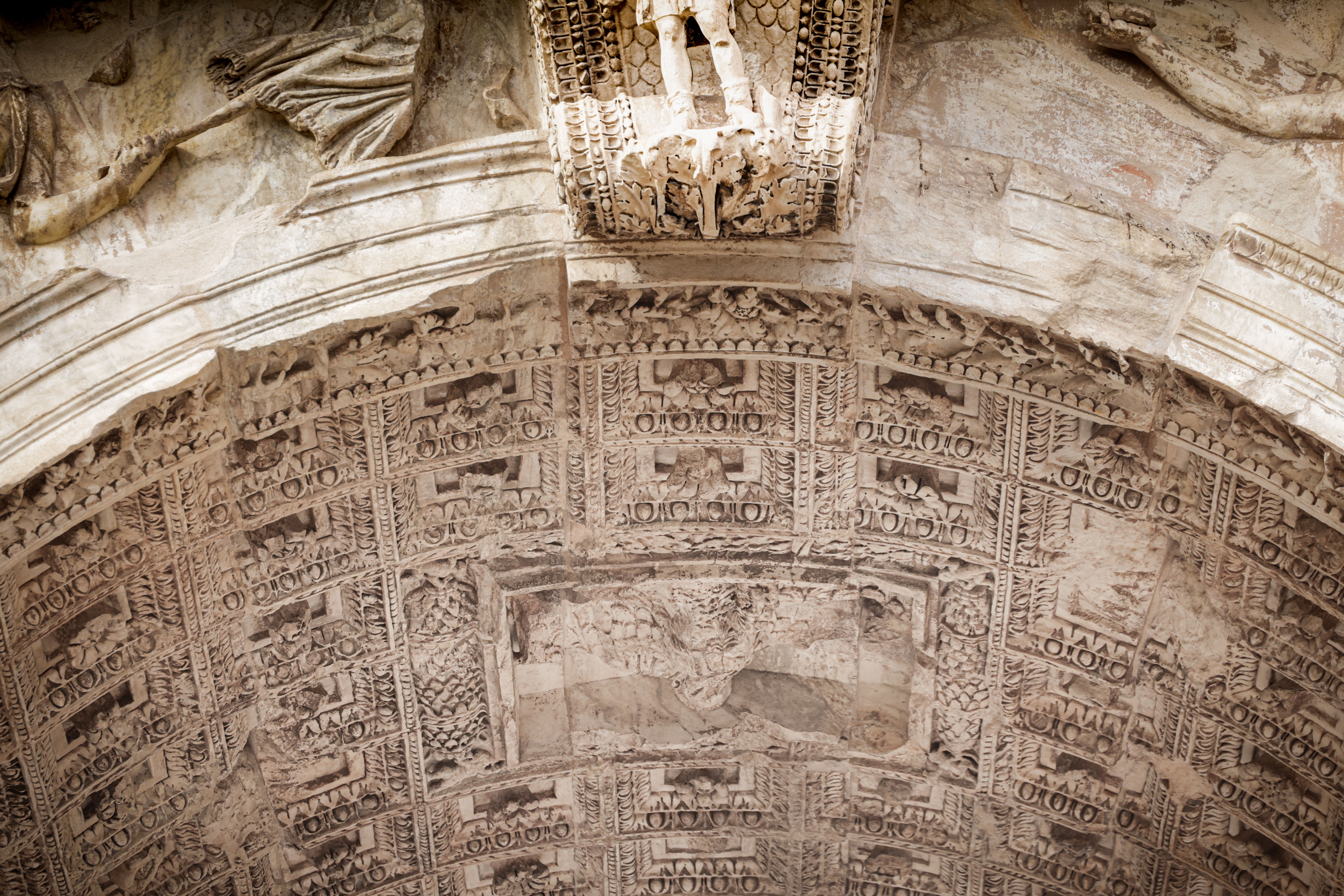 Close-up of an intricately carved relief on an ancient Roman archway, showcasing detailed artistry in stone.
