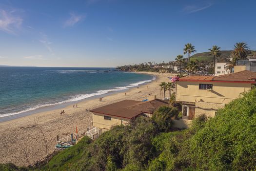 A picturesque view of a sandy beach in Laguna Beach, California with clear skies and ocean waves.