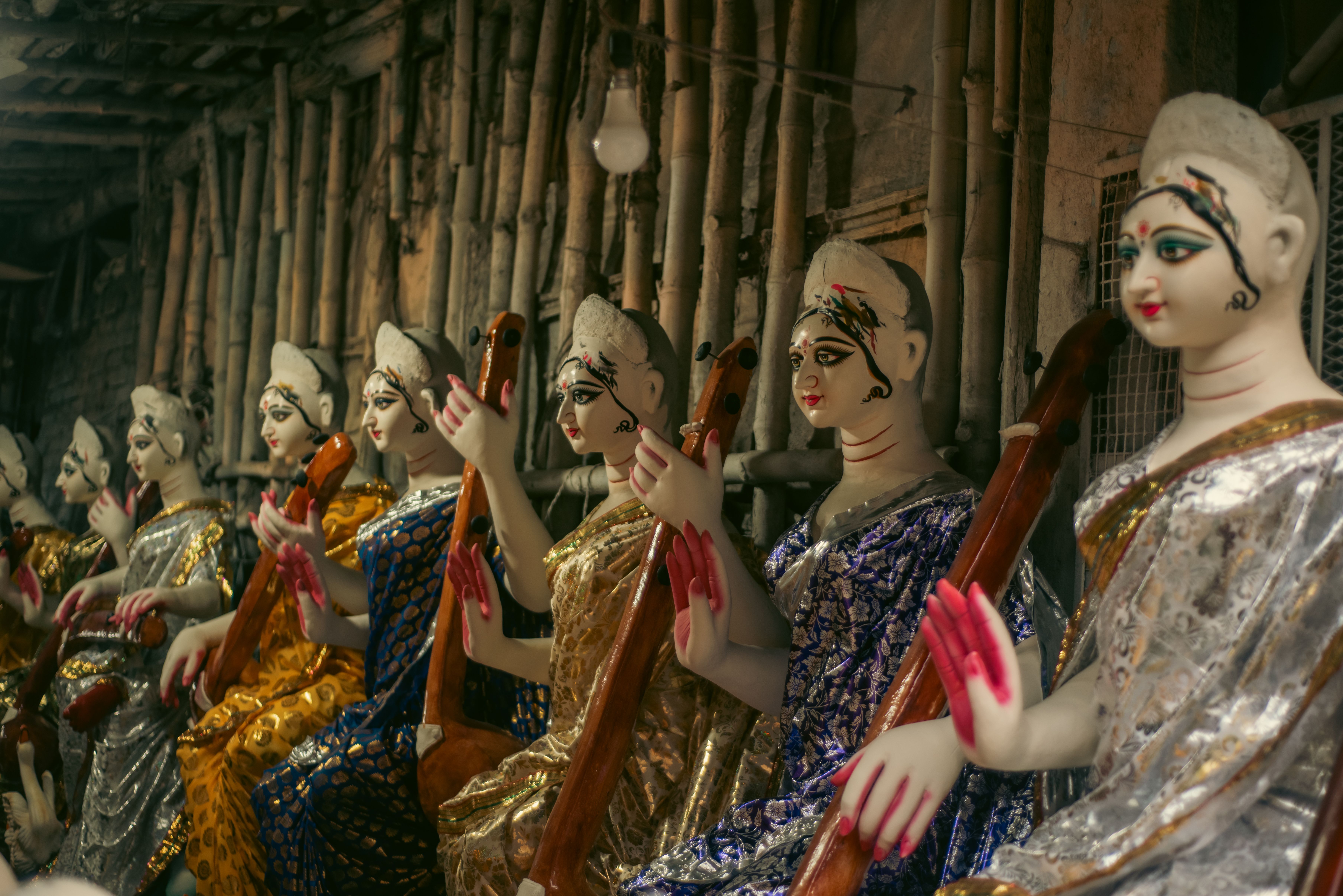 Vibrant Indian statues of women in traditional attire, lined up for crafting.