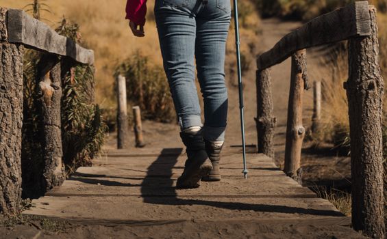 A person hiking on a rustic wooden bridge in rural Mexico, during daytime.