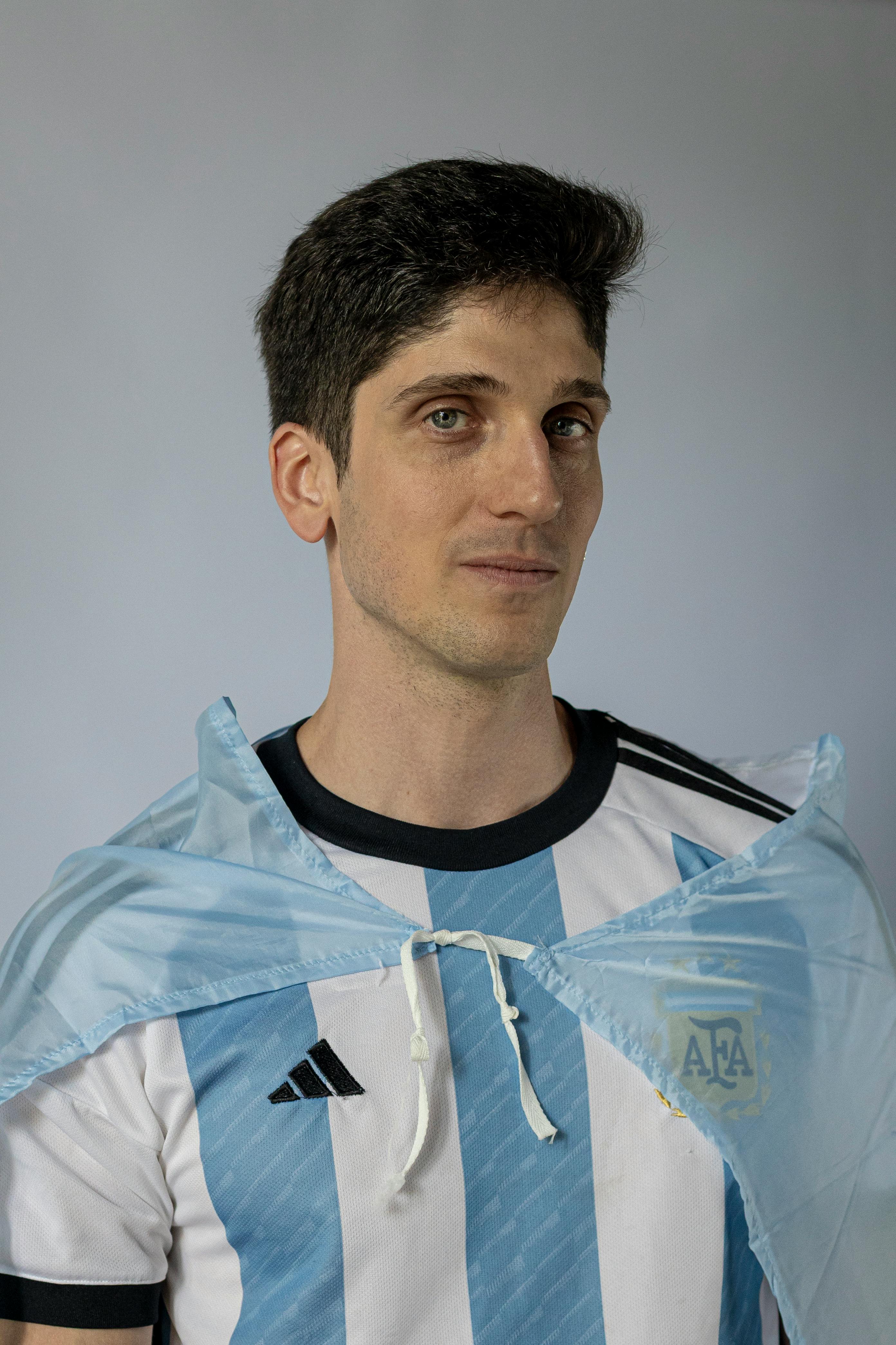 Portrait of a man wearing an Argentina football jersey and cape, representing national pride.