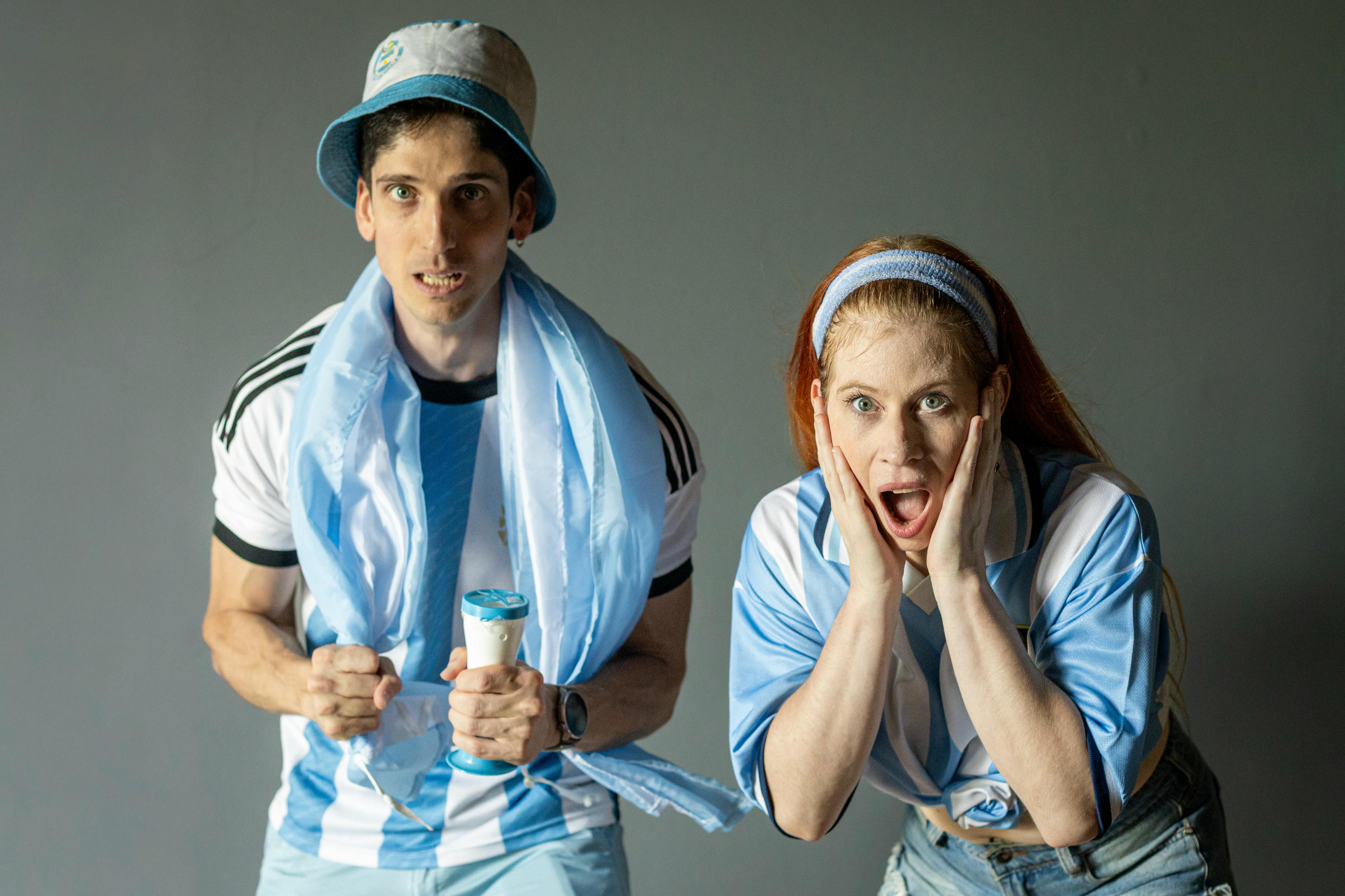 Two passionate Argentine football fans expressing excitement indoors in Buenos Aires.