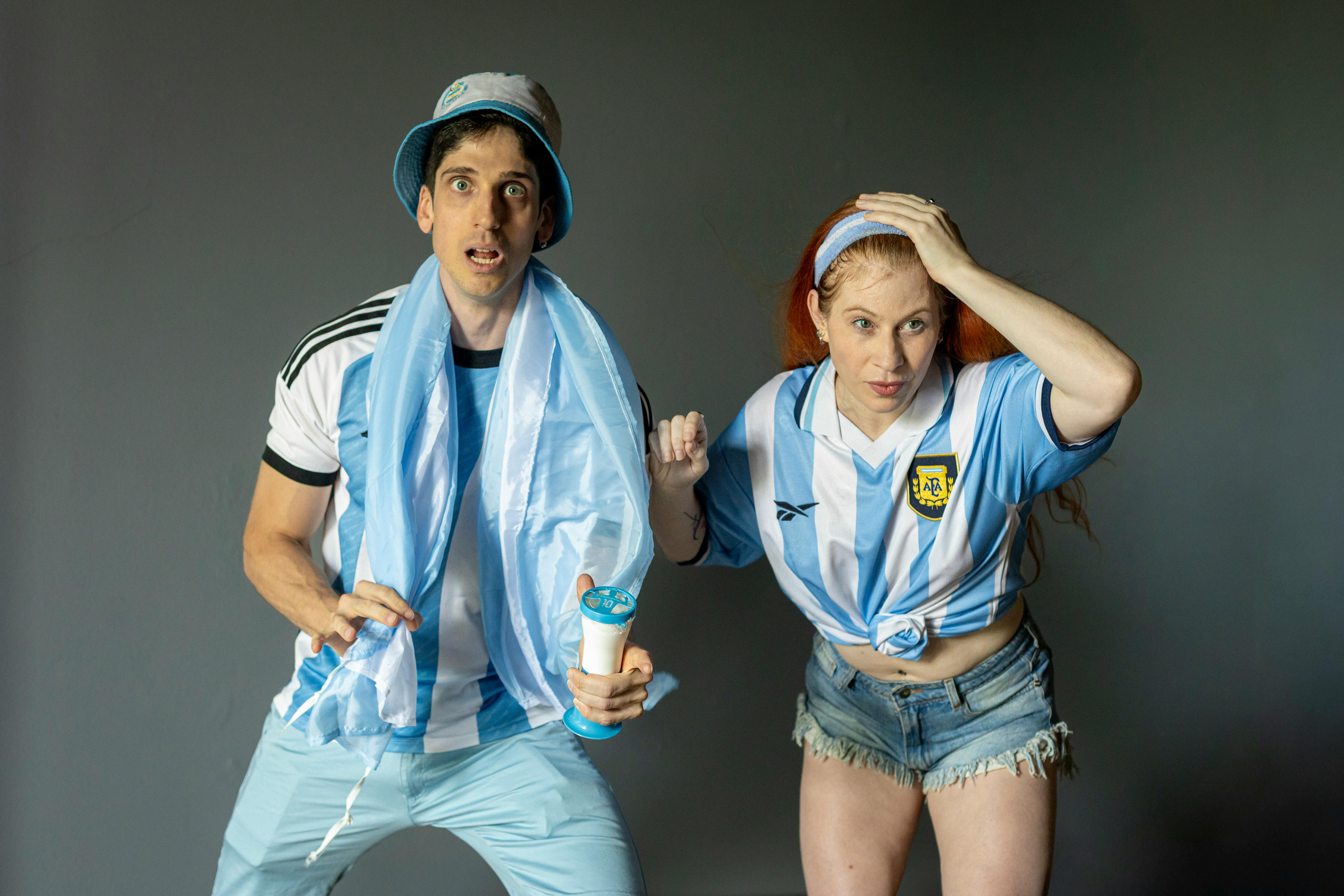 Excited Argentine fans in team jerseys, intently watching a sports event indoors.