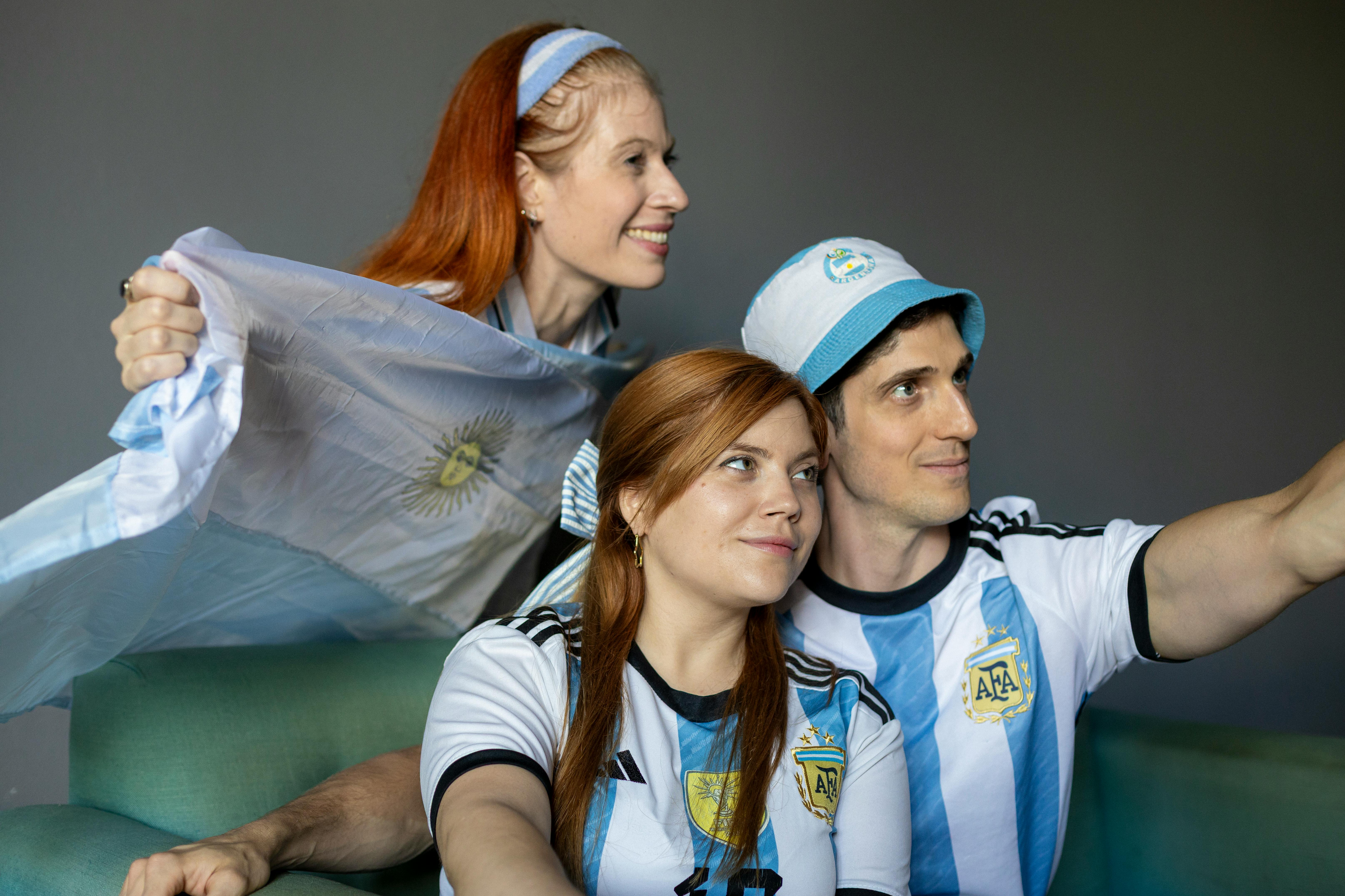 Fans wearing Argentina jerseys cheer while watching a match indoors. Captured in Buenos Aires.