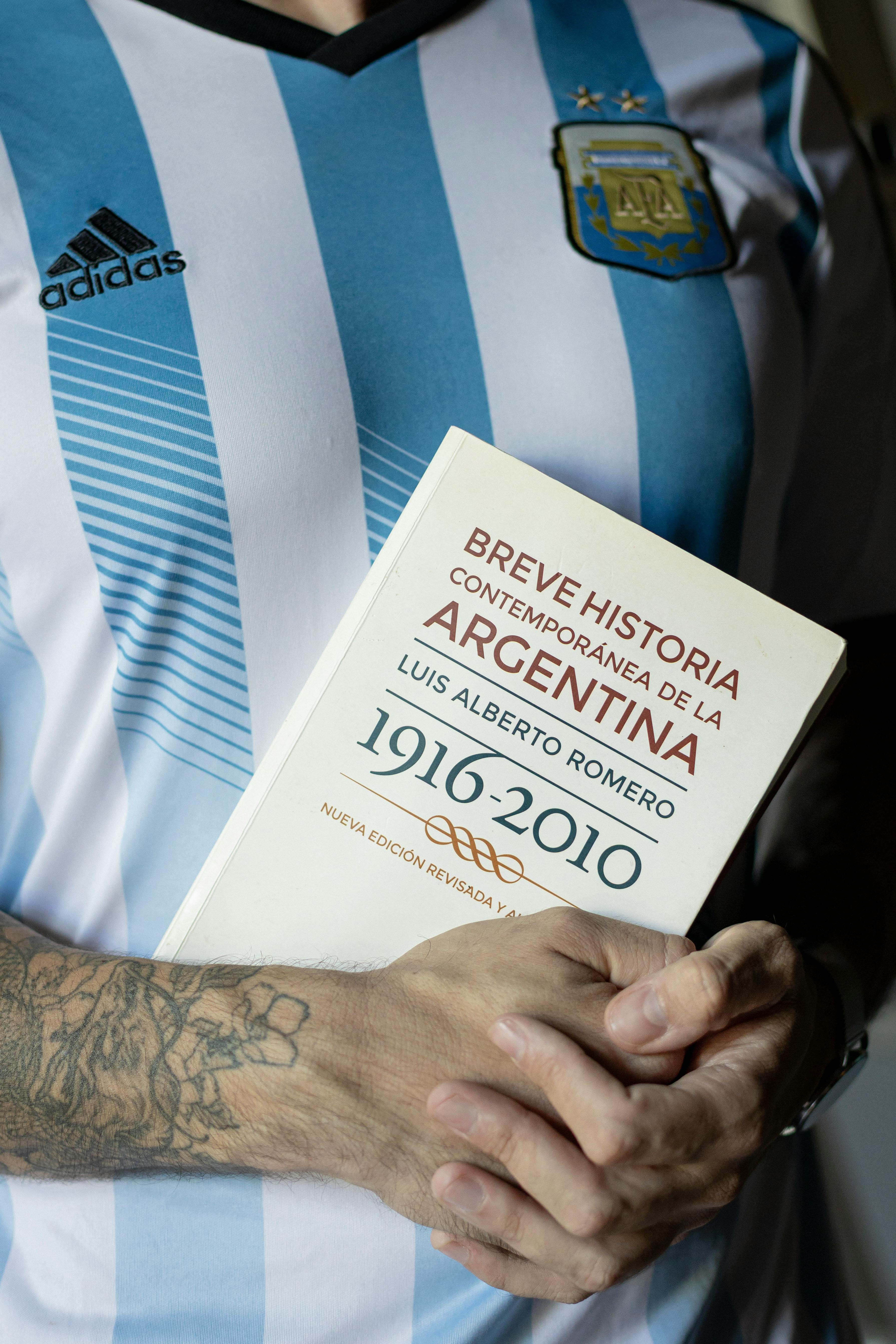 Person in Argentina jersey holding a history book of Argentina.