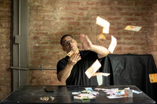 A man playfully throws Argentine peso bills in an interior setting in Buenos Aires, Argentina.