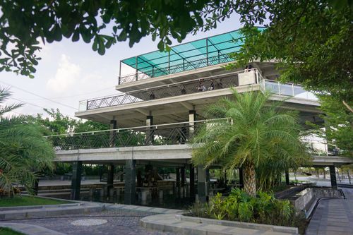 Free A modern open-air cafe surrounded by lush palm trees, offering a serene relaxation spot near Phnom Penh. Stock Photo