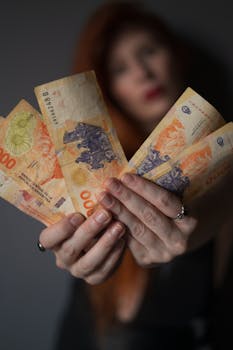 Close-up of a person holding Argentine peso banknotes, showcasing currency details.