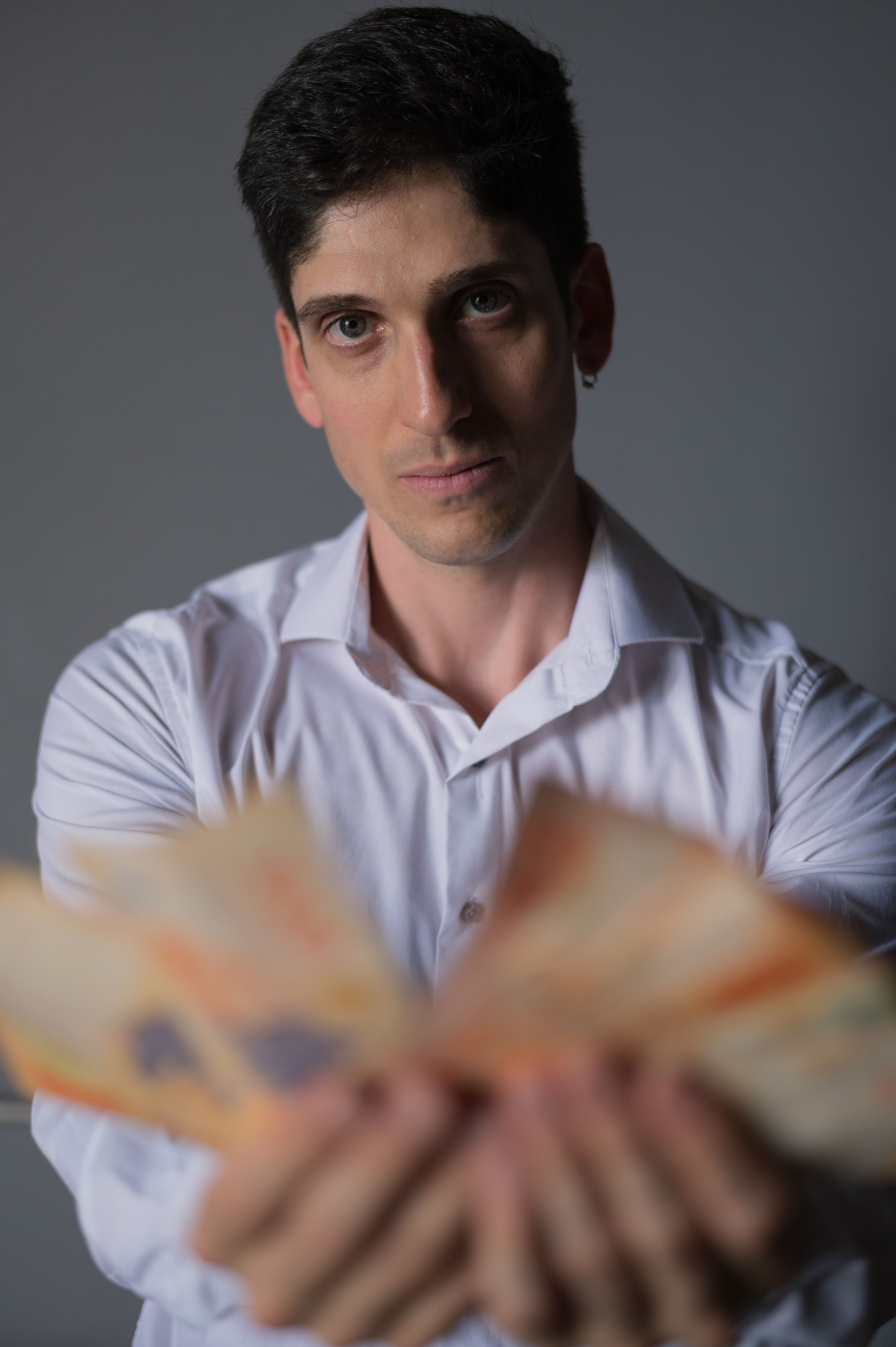 Man Holding Argentine Peso Notes Indoors