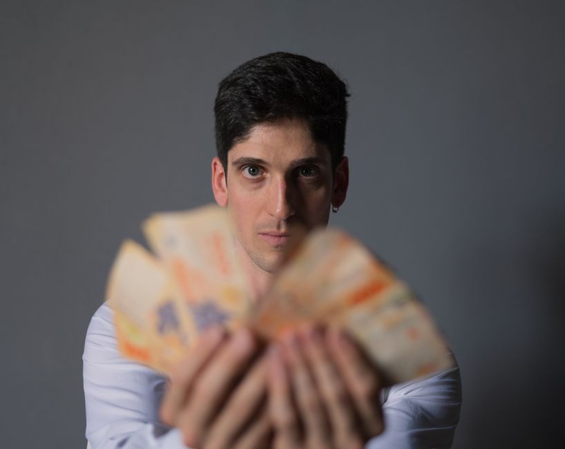 Como a Criatividade Pode Transformar sua Vida Financeira 2 Focused portrait of a man holding Argentine Peso bills, emphasizing financial concepts.