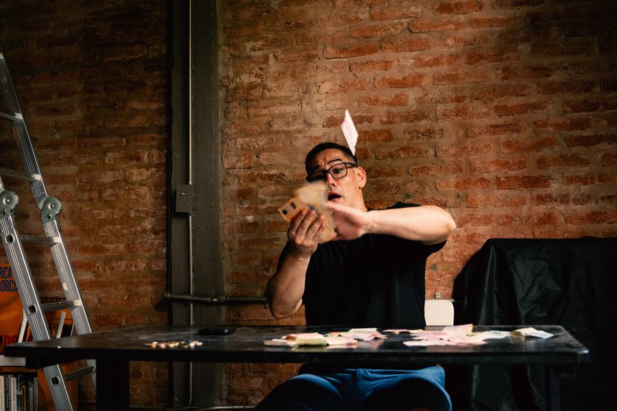 Man enthusiastically handling money indoors against rustic brick background.