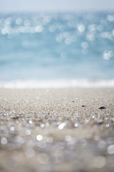 Close-up of a sandy beach with sparkling water in the background, evoking a peaceful summer vibe.