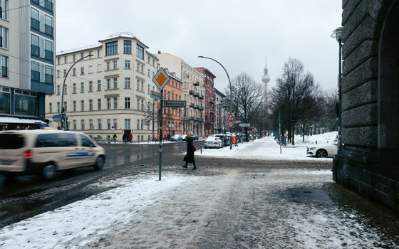 A snowy Berlin street scene featuring the iconic TV tower during winter.