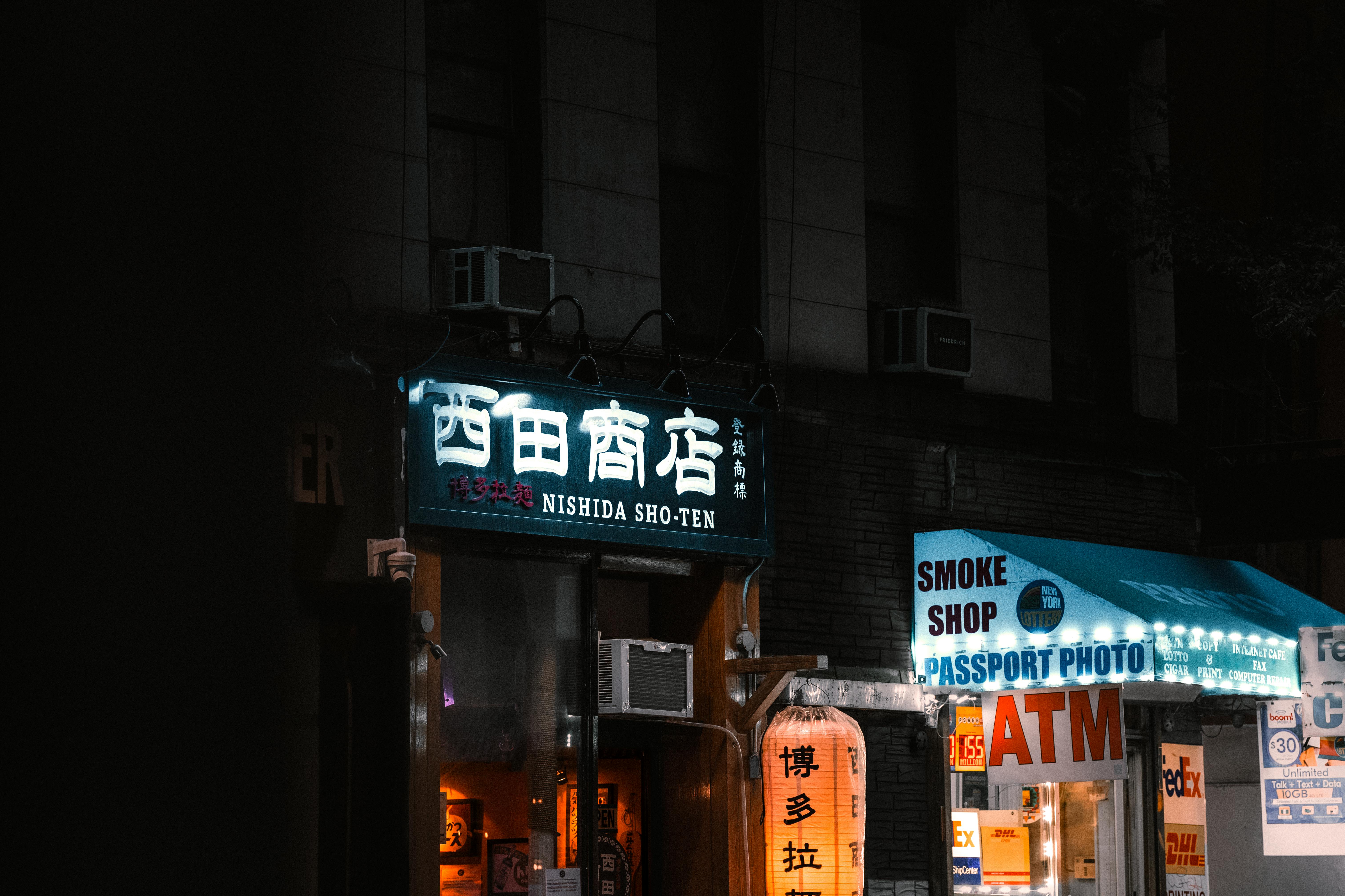 бесплатная Витрина магазина Nishida Sho-Ten, освещенная неоновыми вывесками, ночью на оживленной улице Нью-Йорка. Стоковое фото