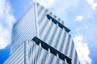 低角度视角下的现代玻璃摩天大楼，以其独特的建筑设计，映衬着充满活力的蓝天