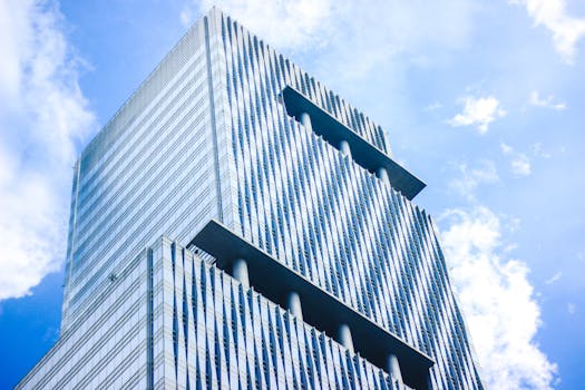 低角度视角下的现代玻璃摩天大楼，以其独特的建筑设计，映衬着充满活力的蓝天