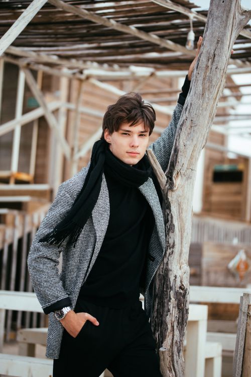 Free Young man in winter attire posing outdoors by a rustic structure. Stock Photo