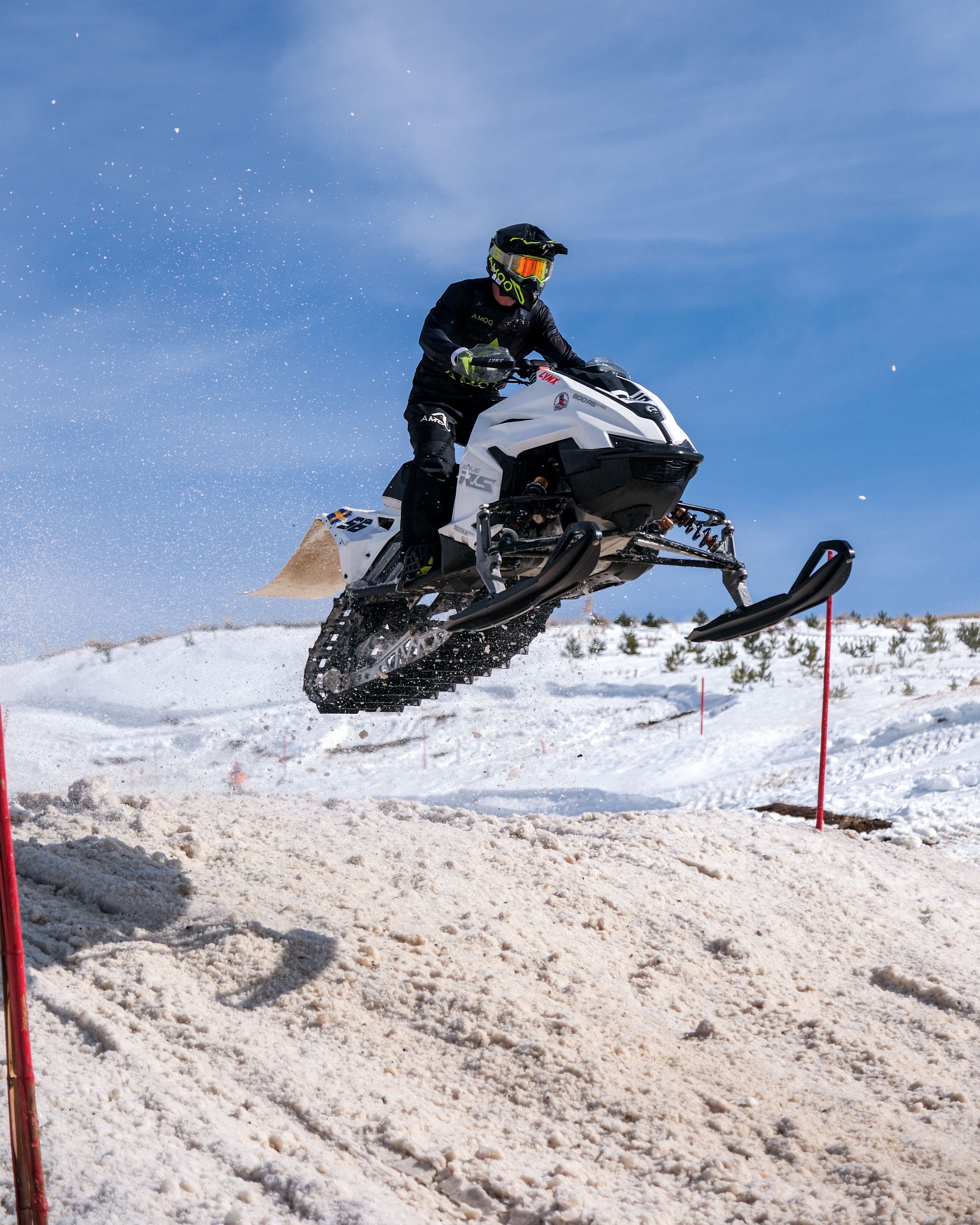 Rider performs a high jump with a snowmobile in a scenic winter landscape.
