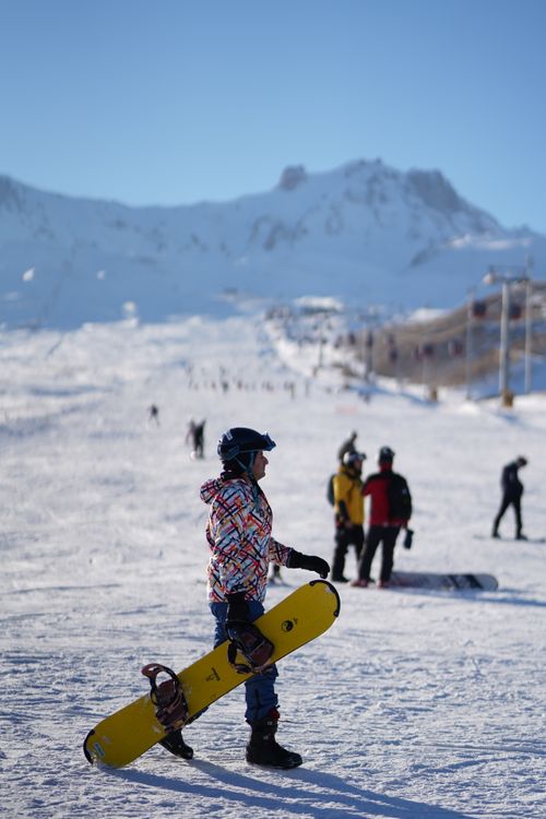 Free A snowboarder stands ready on a sunny snow-covered mountain slope, perfect winter adventure. Stock Photo