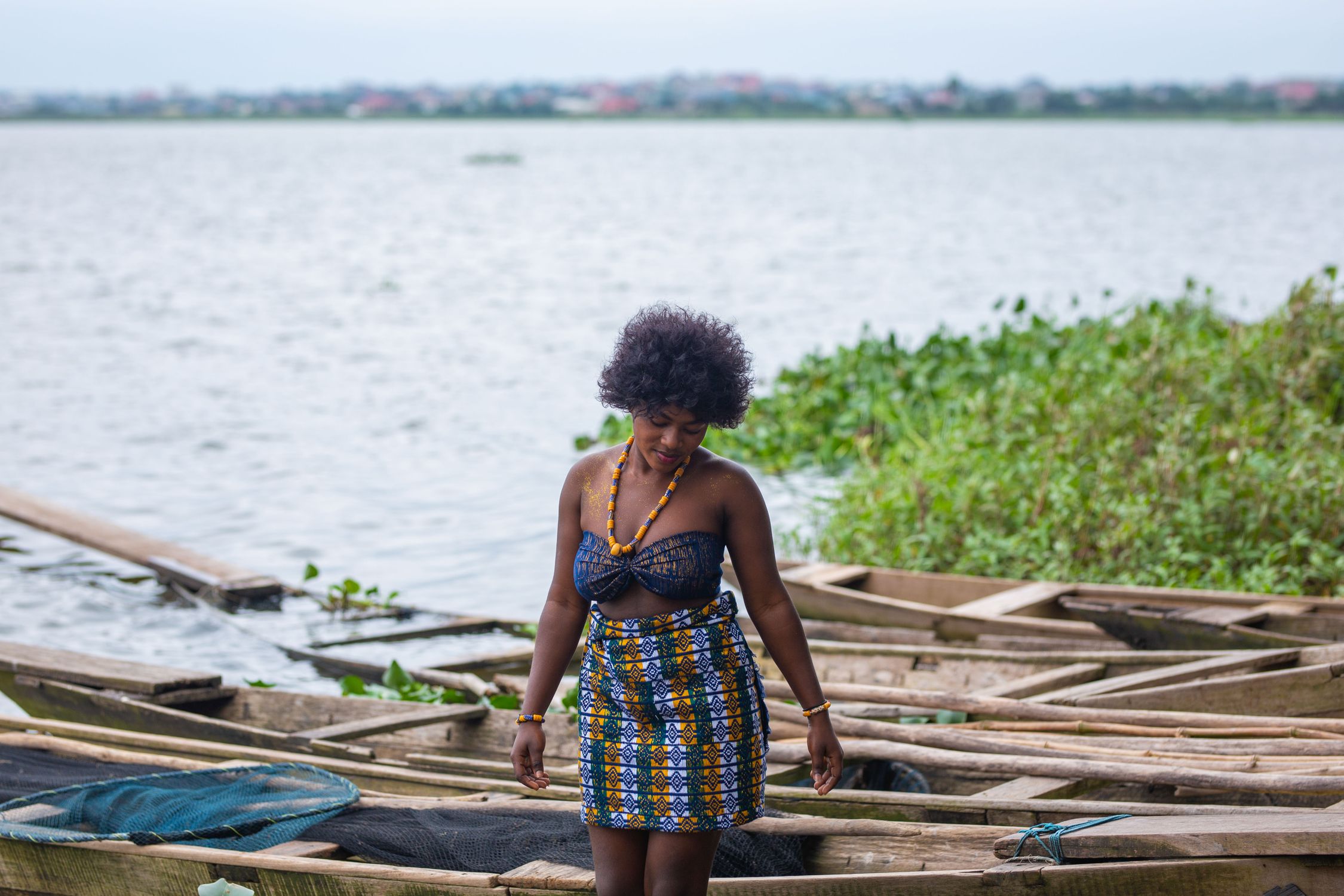 A woman in local clothing walking by wooden boats on Lake Volta, Ghana.