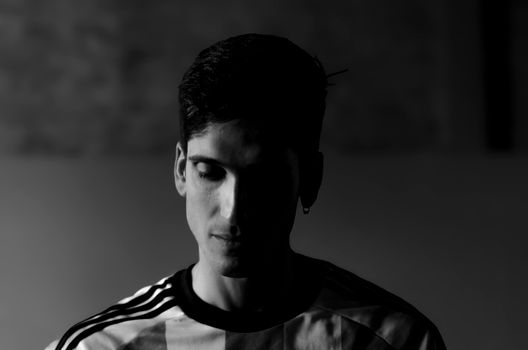 Dramatic black and white portrait of a man with soft shadows and thoughtful expression.