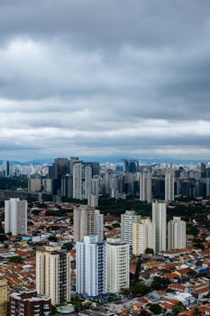 俯瞰繁华的城市景观，壮观的云层下高耸的摩天大楼和密集的城市建筑尽收眼底