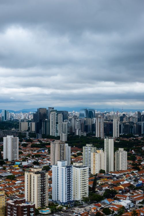 Free Aerial view of a bustling cityscape under dramatic clouds, showcasing tall skyscrapers and urban density. Stock Photo