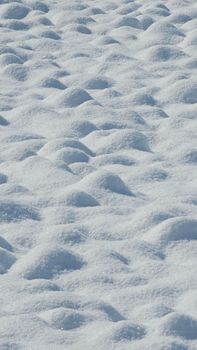 Undulating snow dunes create a serene winter landscape with sparkling textures.