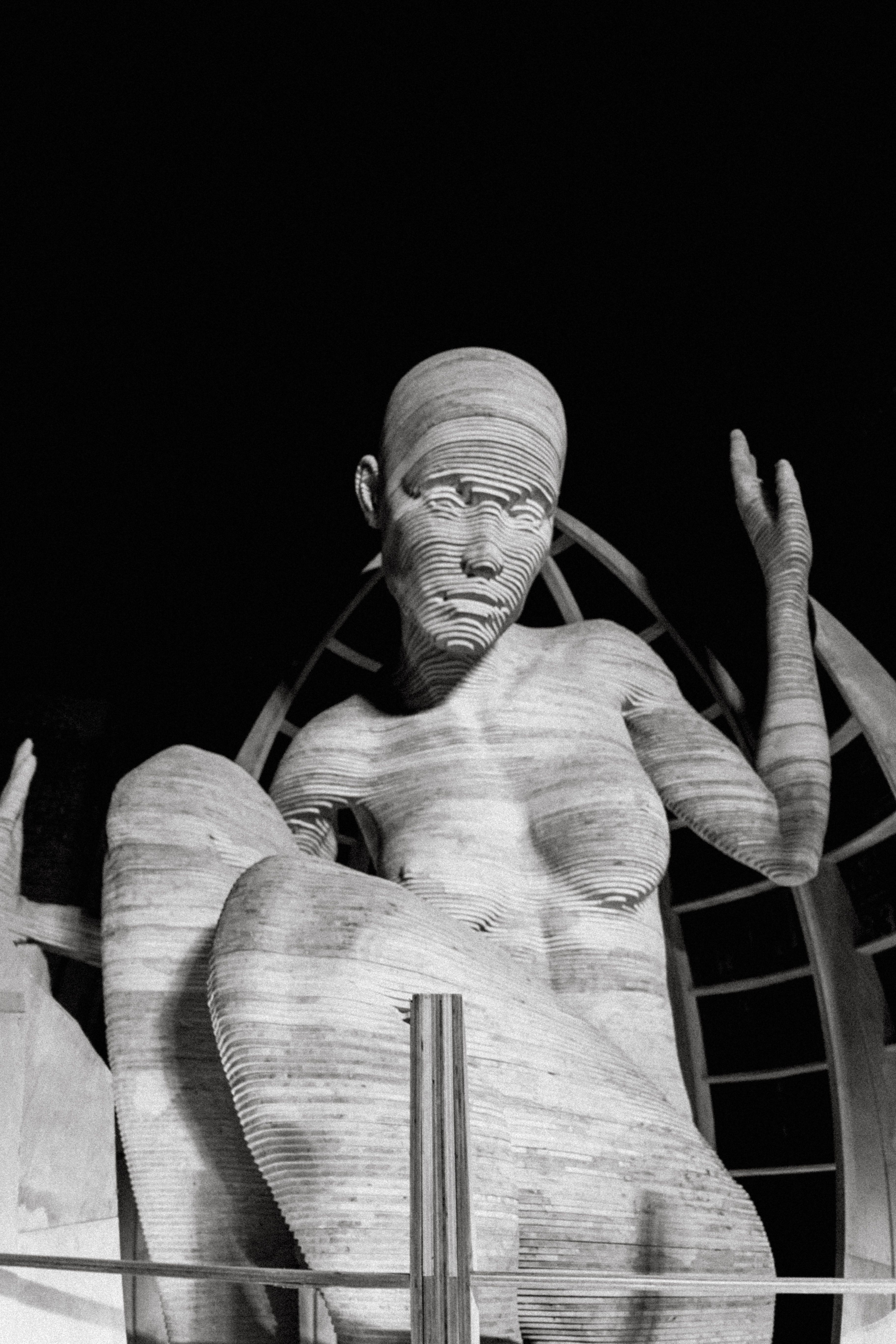 Photo en noir et blanc d'une statue dramatique, élégamment éclairée sur un fond sombre.