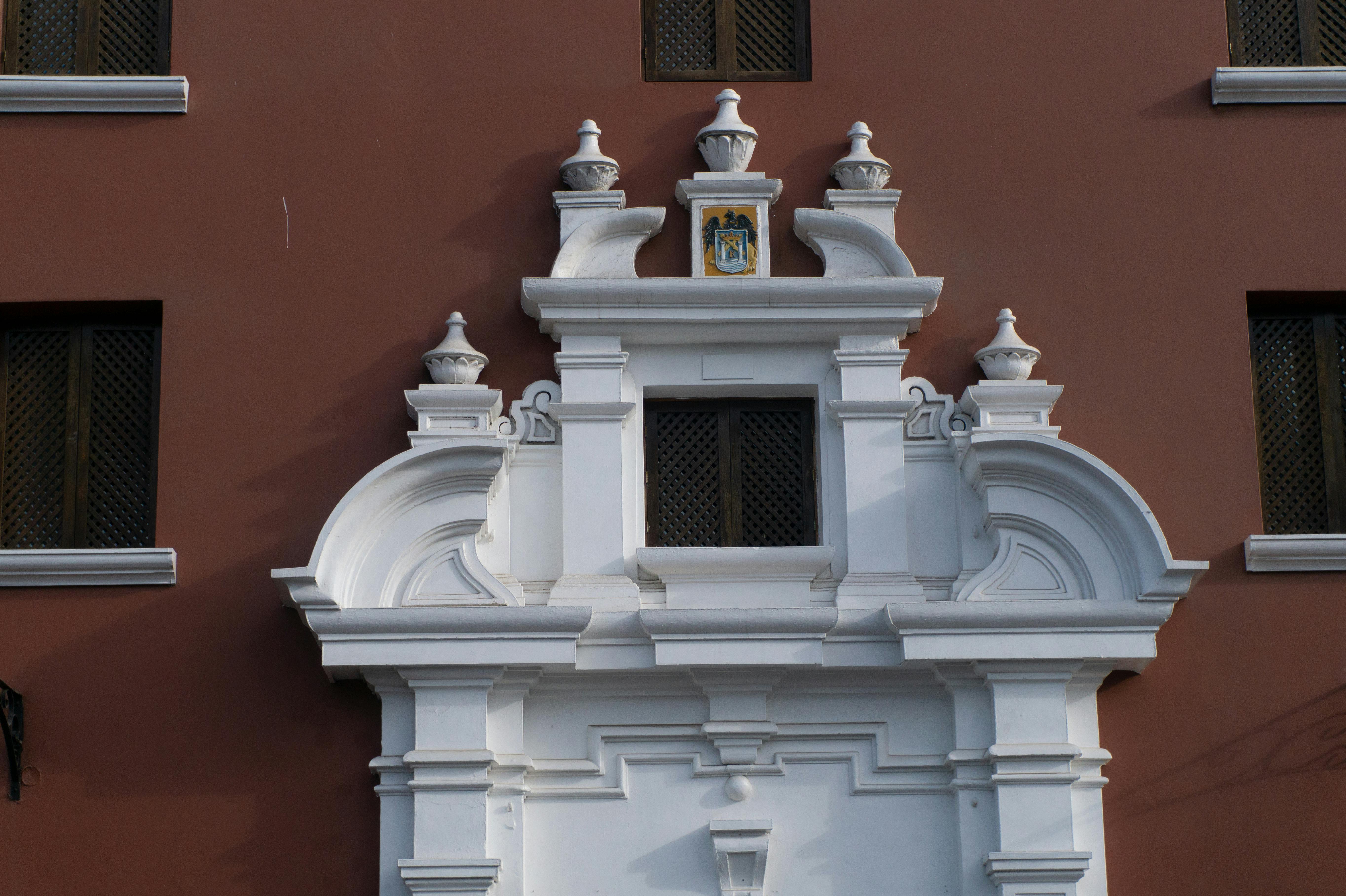 Gratuit Vedere detaliată a unei fațade baroce albe pe un perete roșu, cu elemente arhitecturale complexe. Fotografie de stoc