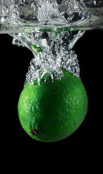 在黑色背景下，充满活力的绿酸橙在水中溅起水花