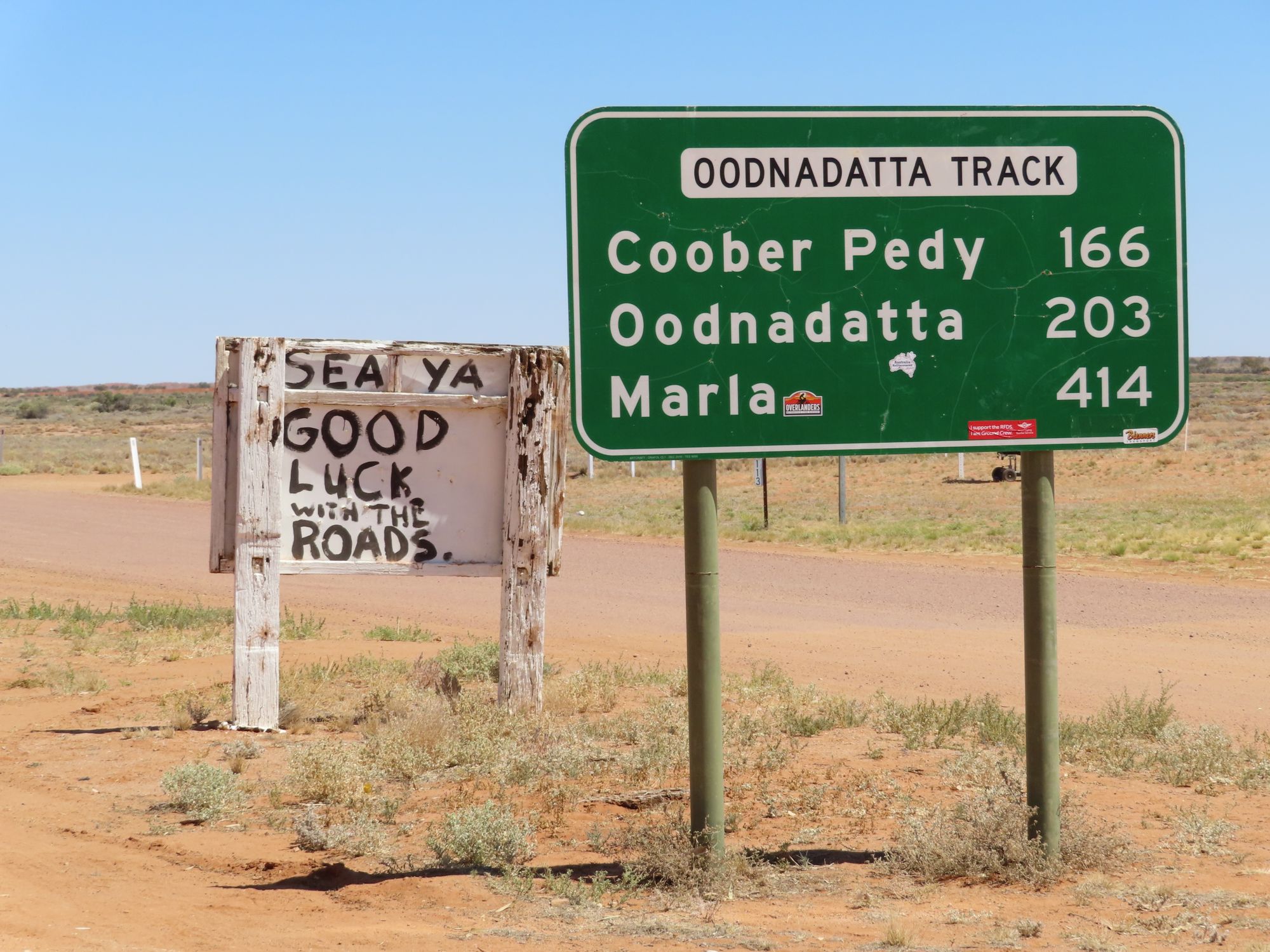 Road signs on the Oodnadatta Track in the Australian outback, featuring humorous local signage