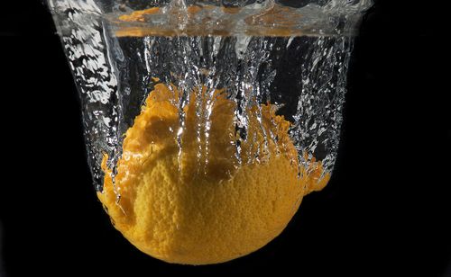 Free A vibrant lemon dives into water, creating an energetic splash against a black background. Stock Photo