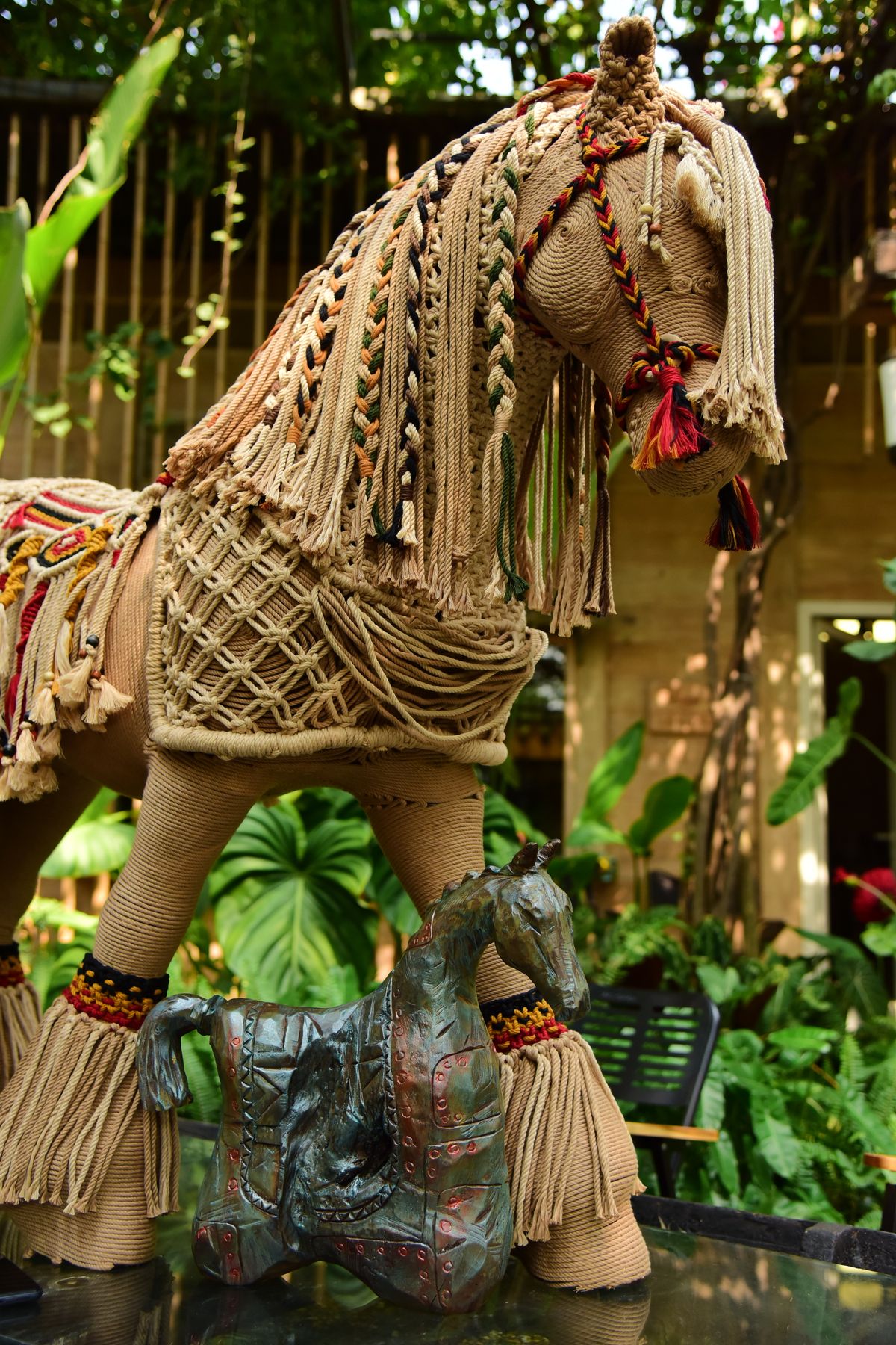 An artistic macrame horse displayed in a lush garden setting
