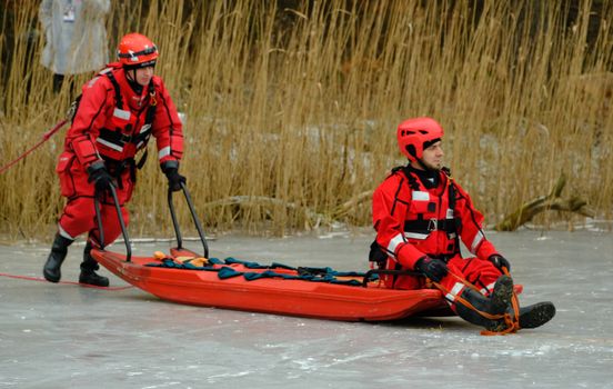 Rescue team performing ice rescue operation on a frozen lake with a sled.