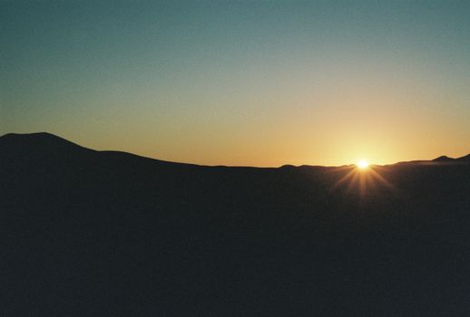 A serene silhouette of mountains against a golden sunset, capturing nature's beauty.