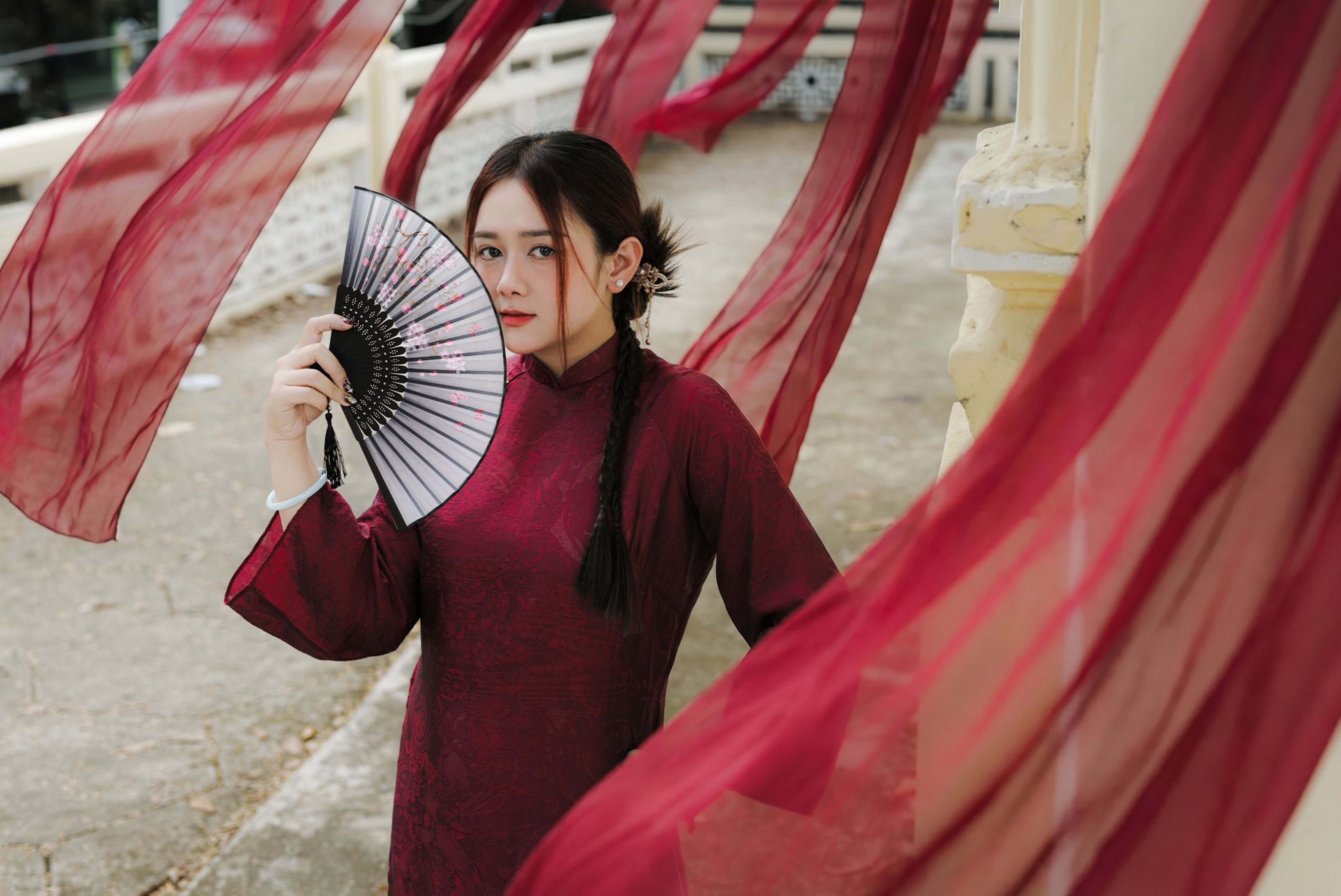 Elegant Woman with Fan Amid Flowing Fabric · Free Stock Photo