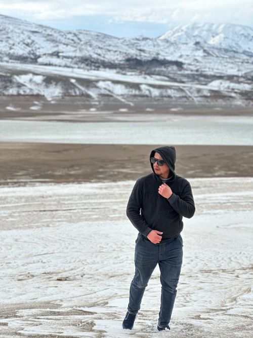 Free A man in a hoodie wanders through snowy landscapes in Uzbekistan's mountains. Scenic and serene. Stock Photo
