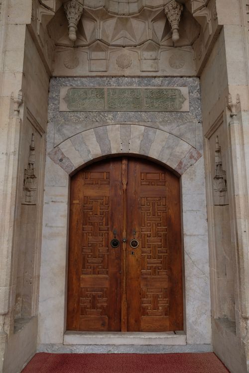 Free Elegant wooden door with geometric designs in a stone archway, showcasing cultural artistry. Stock Photo