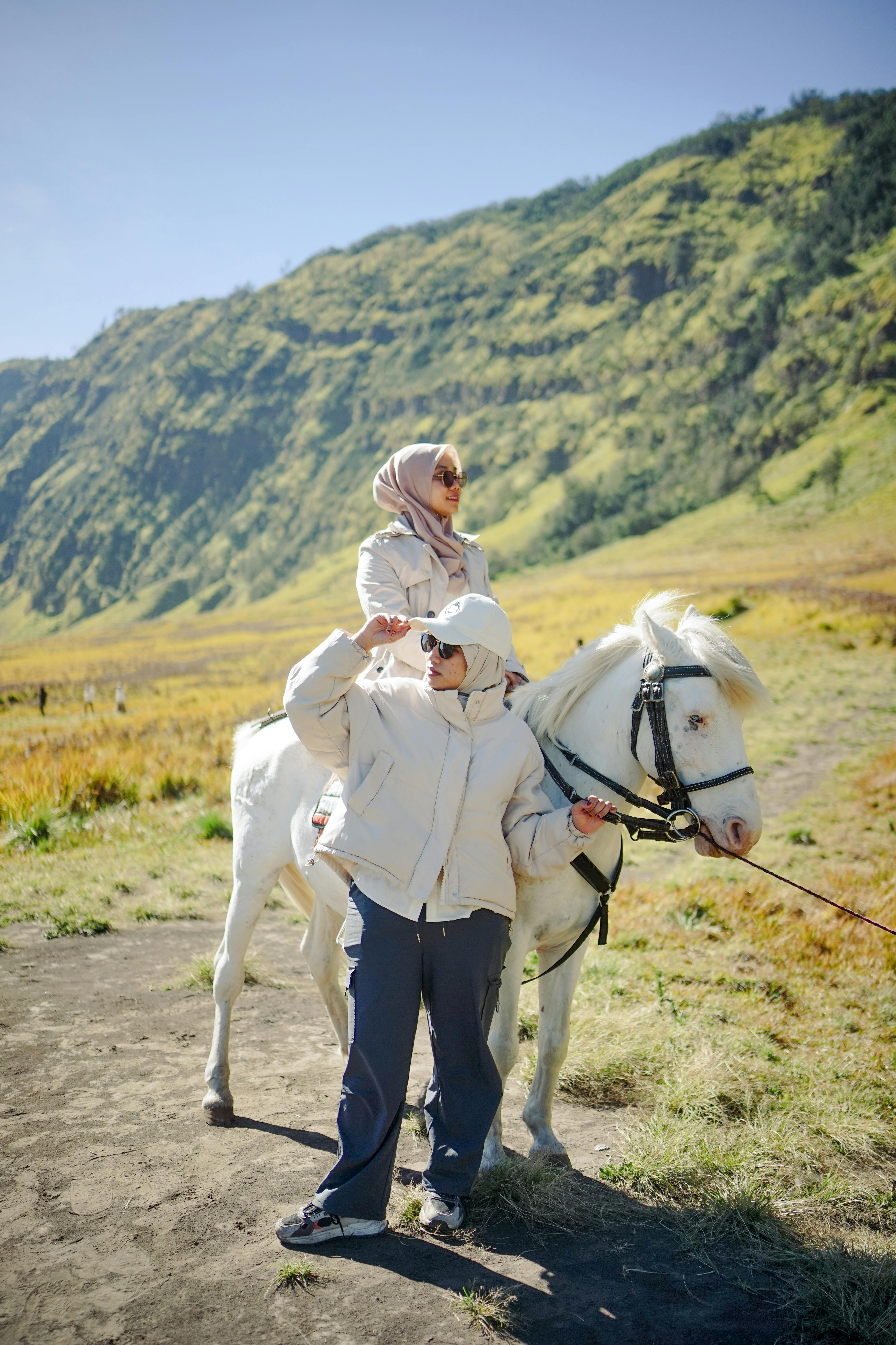 Two women enjoy a scenic horseback ride in East Java, Indonesia's picturesque landscape.