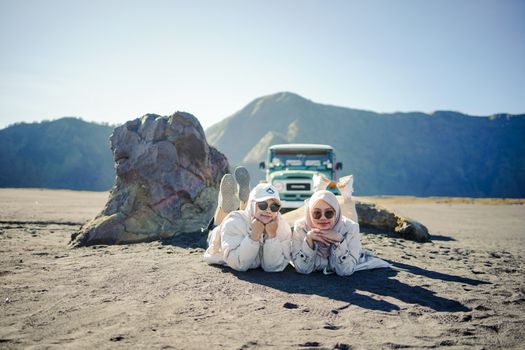 Two friends enjoy a relaxing day in the sandy plains of Mount Bromo, East Java.