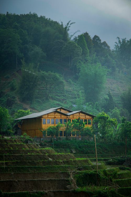 Free A serene wooden house nestled in a green mountainous landscape under misty skies. Stock Photo