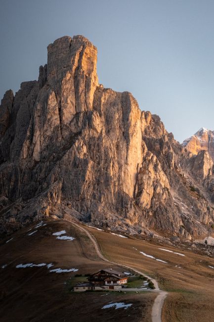 Sunrise view of a chalet in the Dolomites with rugged mountains in the background.
