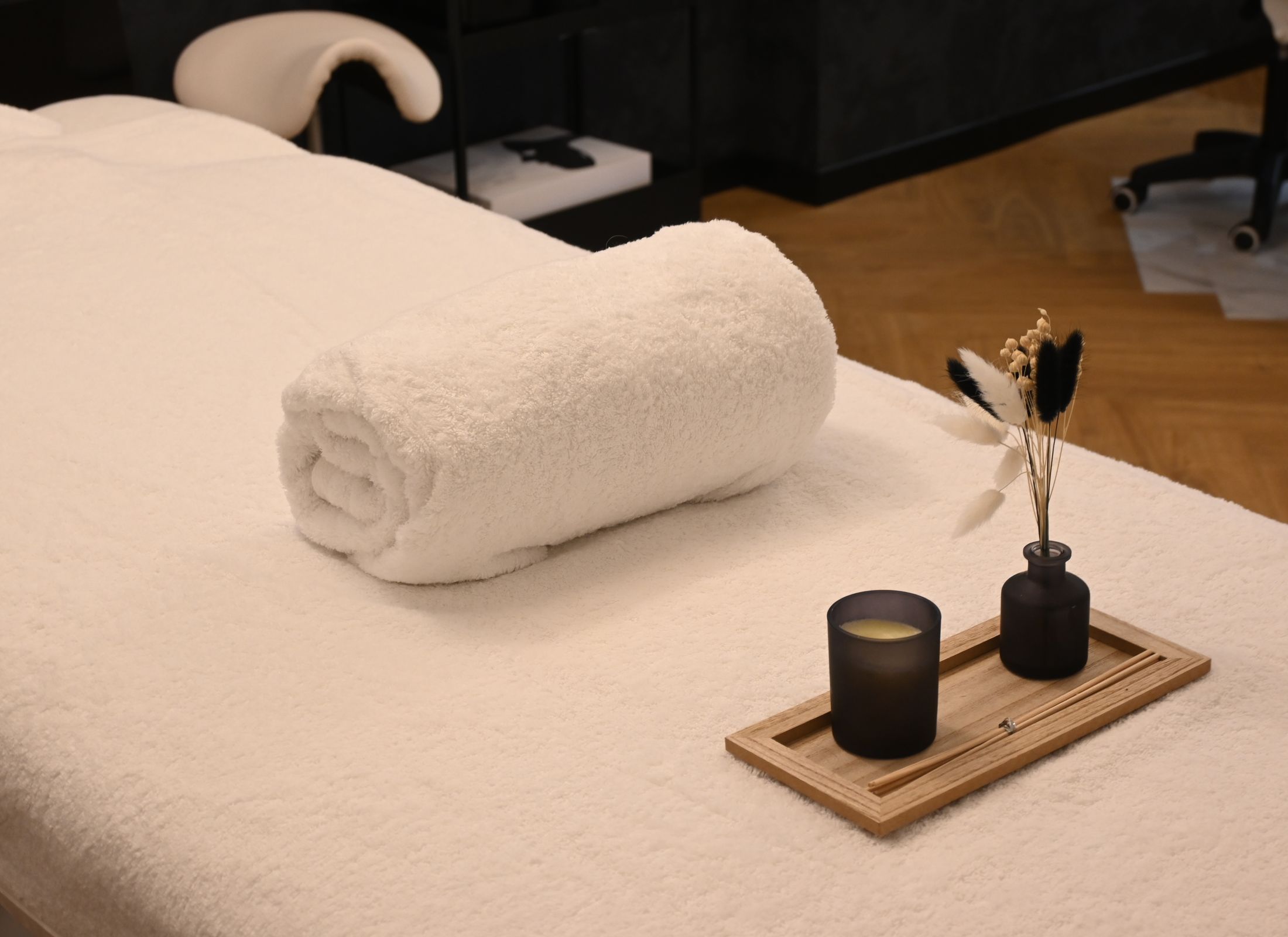 A quiet treatment table set with a rolled towel and a lit candle.