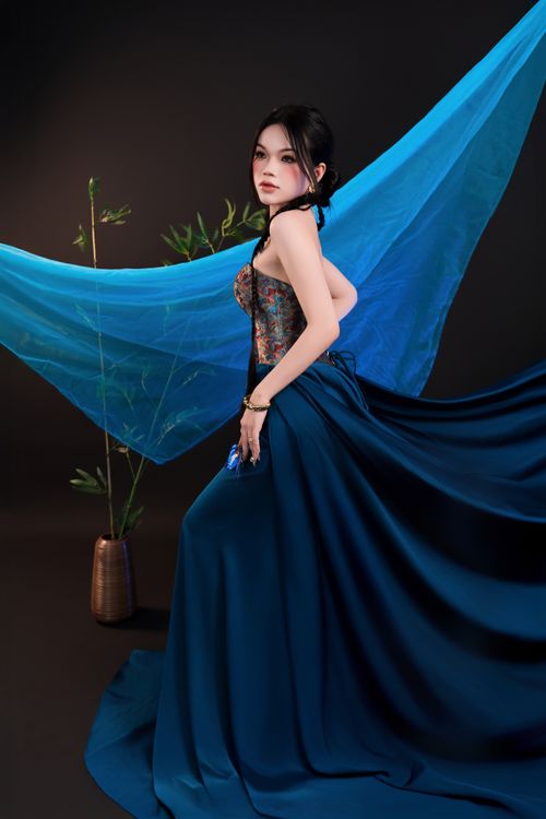 Free A woman poses elegantly in a blue dress against a striking artistic backdrop indoors. Stock Photo