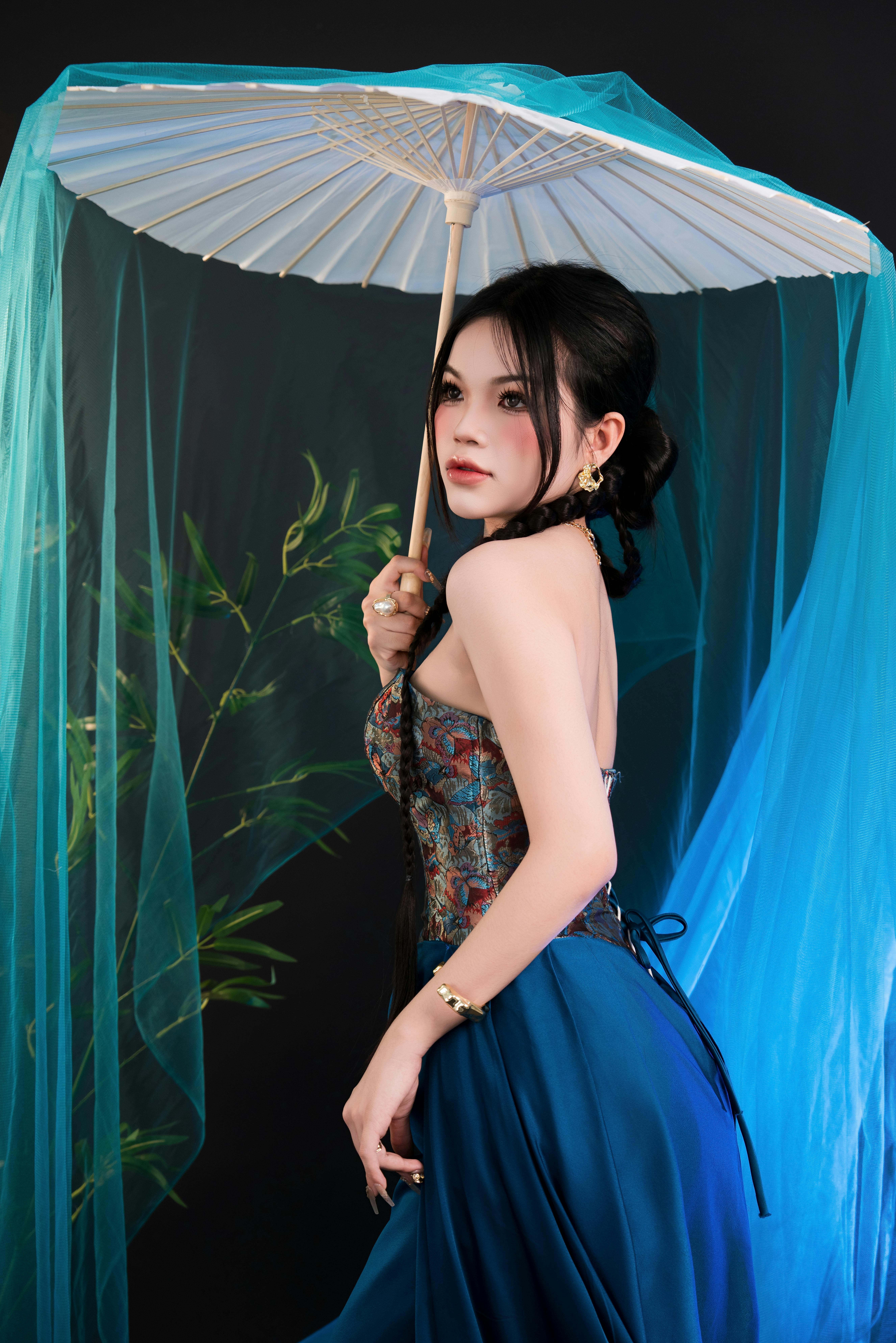 Portrait of an Asian woman holding a traditional umbrella, exuding elegance and cultural beauty.