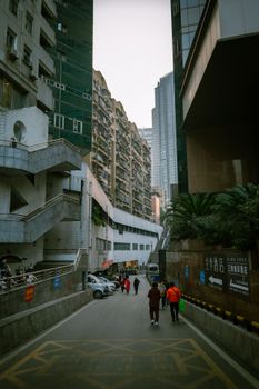 City alley with tall residential buildings and people walking, an urban scene.