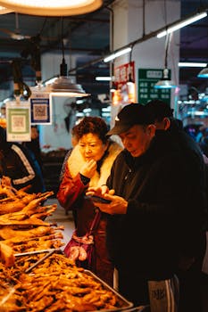 A diverse group of adults examines poultry at a lively indoor market, rich with cultural exchange.